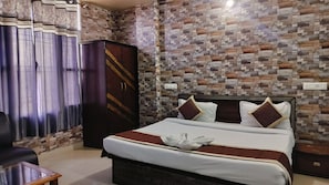 A hotel room with a bed, curtains, a wardrobe, and a wall with a mosaic pattern. - Hotel Binwa View (Baijnath)