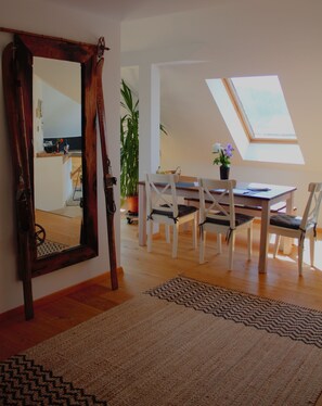 Ein Essbereich mit Holztisch und -stühlen, einem großen Spiegel und einem Oberlicht.