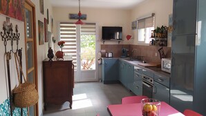 A kitchen with blue cabinets, a refrigerator, a sink, and a dining table with chairs.