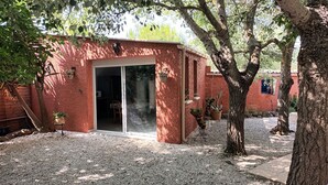 A small brick building with a sliding glass door, surrounded by gravel and potted plants.