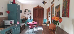 Une cuisine équipée d’un four à micro-ondes, d’une table à manger avec des chaises, d’un meuble en bois et d’un vase rempli de fleurs.