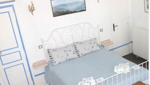 Une chambre à coucher avec un lit, un banc en bois, un radiateur blanc et un tableau encadré accroché au mur.