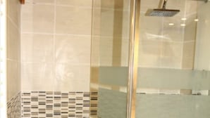 Une douche avec une porte en verre et un pommeau de douche.