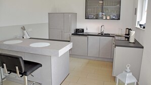 A compact kitchen with a central island, a sink, and a refrigerator. - Holiday Falkenhagen with garden (Sundhagen)