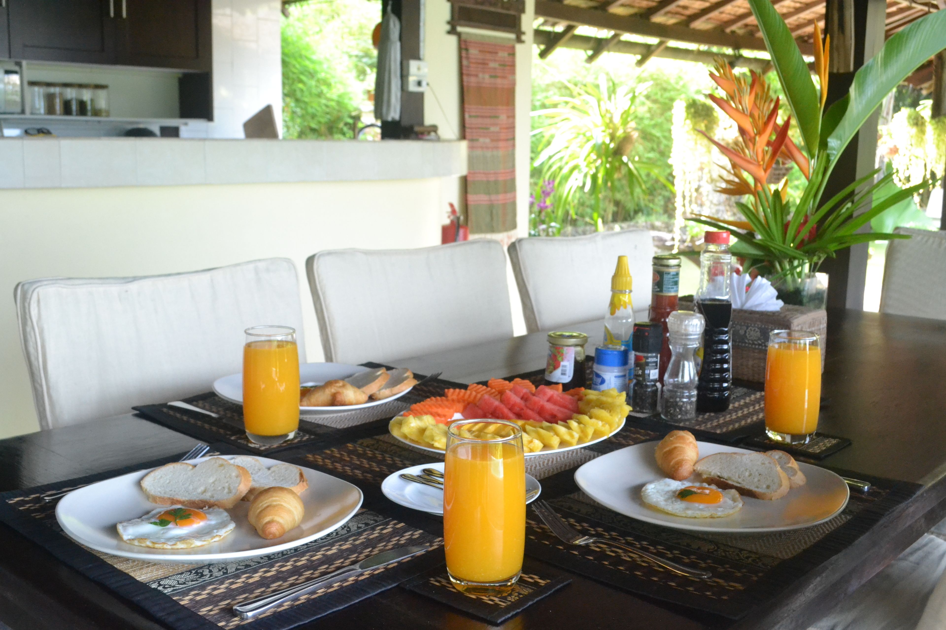 Una mesa de desayuno con platos de comida, vasos de jugo de naranja y diferentes aderezos.