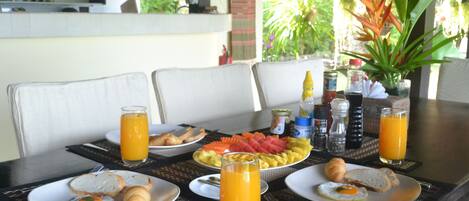 Una mesa de desayuno con platos de comida, vasos de jugo de naranja y diferentes aderezos.