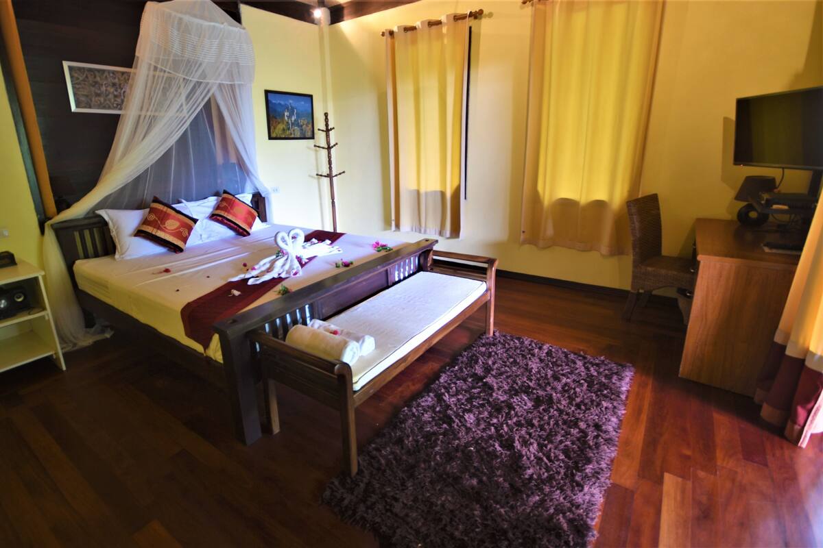 Un dormitorio ordenado con cama, mesita de noche y televisor.