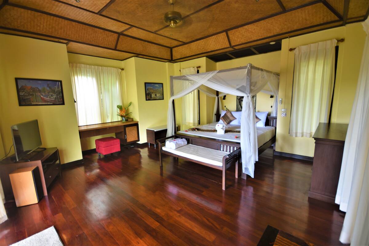 Una habitación con cama, escritorio, televisión y ventana con cortinas.