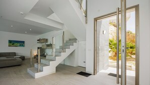 A modern interior with a staircase, a sofa, and a door leading outside. - Villa Sophia (Busot)