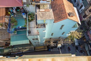 A multi-story building with a red-tiled roof, a balcony with plants, and a visible street below. - Hanoi Wonderland Homestay (Hanoi)