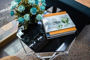 A glass table with a vase of flowers and a stack of books. - Hanoi Wonderland Homestay (Hanoi)