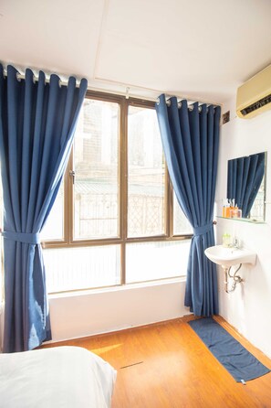 A room with a bed, a window with curtains, a sink, and a mirror. - Hanoi Wonderland Homestay (Hanoi)