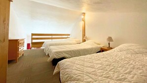 Ein Zimmer mit zwei Betten, einem Holzschrank und einem Nachttisch mit Lampe.
