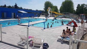 A swimming pool area with multiple pools, a water slide, and a covered seating area. - Camping La Sittelle (Loue)
