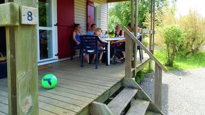 A wooden deck with a covered seating area, a number 8 sign, and a green exercise ball. - Camping La Sittelle (Loue)