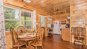 L’intérieur d’une cabane en bois comprend un coin repas, une cuisine et de grandes fenêtres.