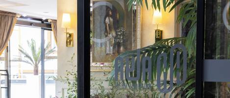 Un vestíbulo de hotel con un espejo grande, plantas en macetas y un letrero que dice "AURORA".