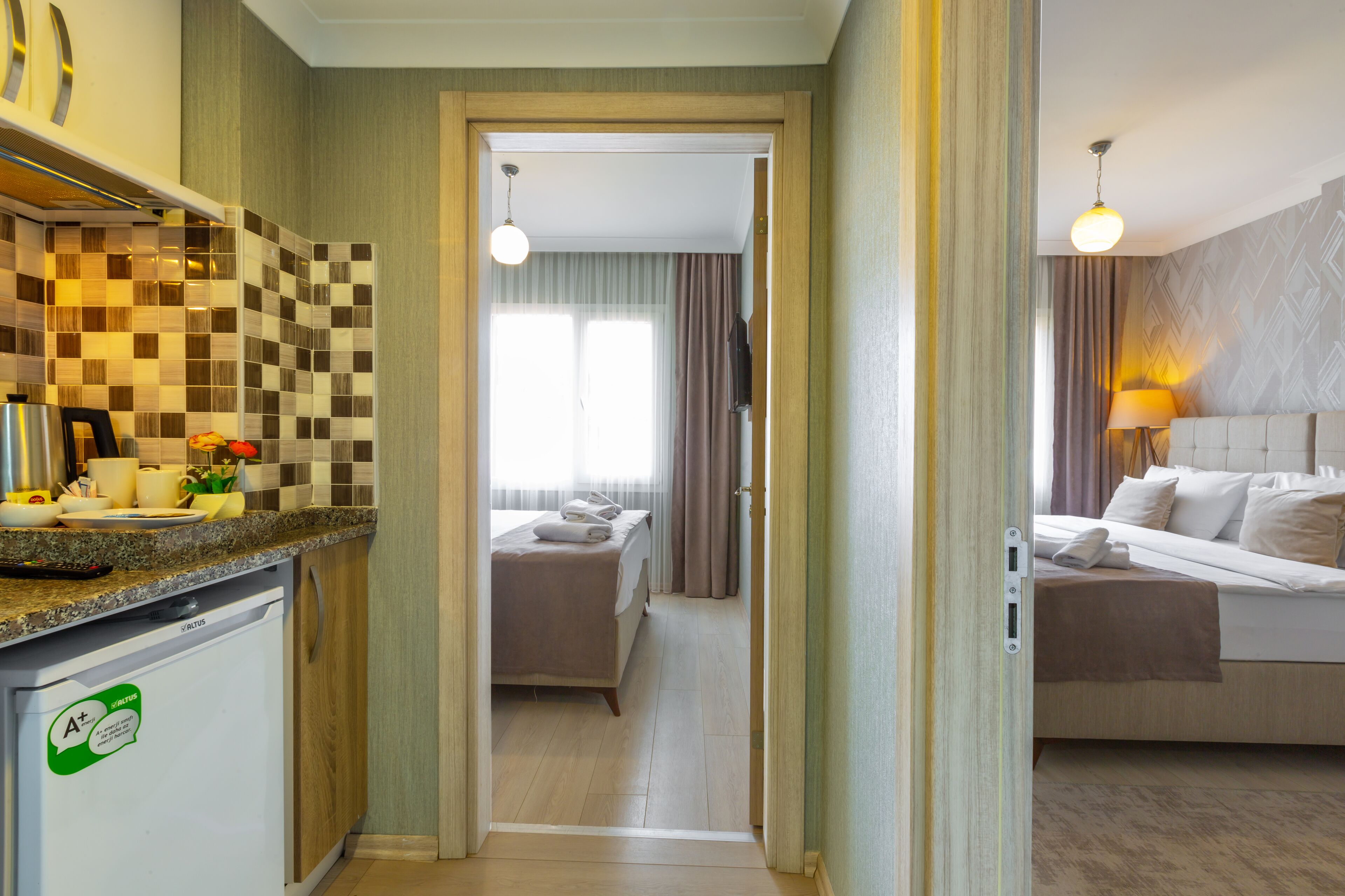 Une chambre d’hôtel équipée d  ’une kitchenette, d’un lit, d’une table de chevet et d’une fenêtre avec des rideaux.