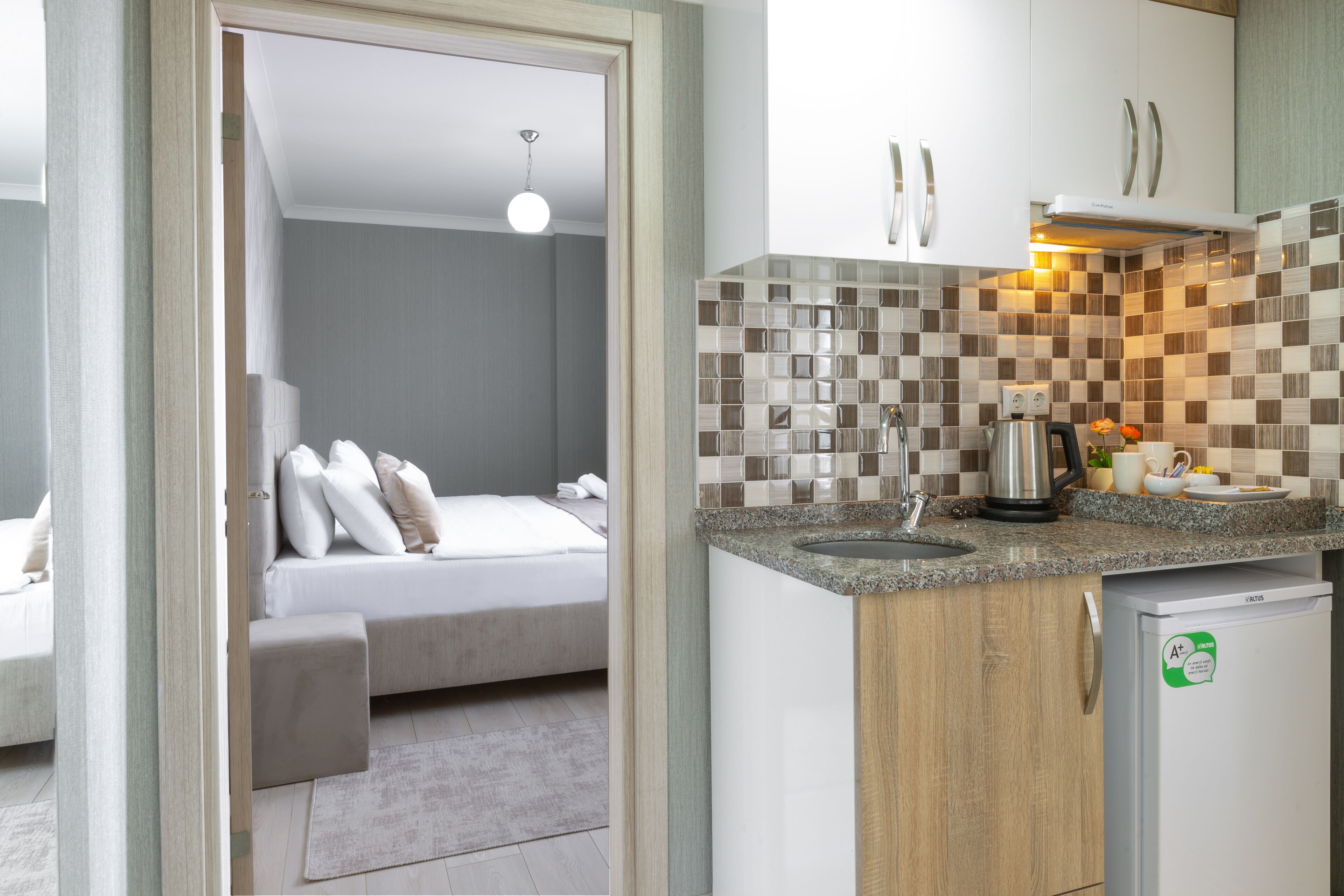 A modern kitchen with a built-in dishwasher, a coffee maker, and a kettle on the counter.