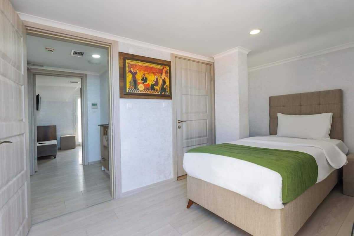 A bedroom with a bed, a door, and a hallway leading to another room.