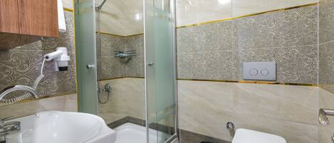 A modern bathroom with a glass-enclosed shower, a white sink, and a toilet.