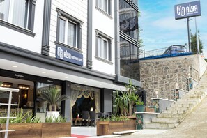 A boutique hotel with a modern facade, outdoor seating area, and a staircase leading to a stone wall.