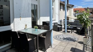 A patio with a glass table and chairs, a potted plant, and a patterned rug. - Apartment in the heart of Bad Pyrmont (Bad Pyrmont)