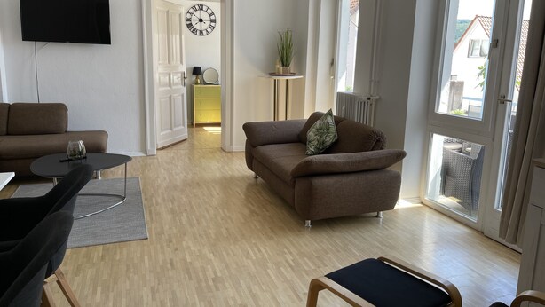 A modern living room with a brown sofa, a small table, and a TV mounted on the wall. - Apartment in the heart of Bad Pyrmont (Bad Pyrmont)