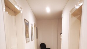 A hallway with wooden flooring, white walls, and a black chair. - Apartment in the heart of Bad Pyrmont (Bad Pyrmont)