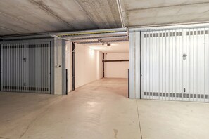 Storage area with metal doors, concrete floor, and exposed pipes.