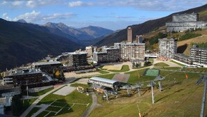 Un complexe hôtelier comprenant plusieurs bâtiments, un terrain de sport et, en arrière-plan, un paysage montagneux.