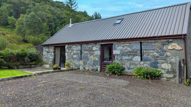 A stone building with a metal roof, a wooden door, and a sign reading "ROSS'S BOTTOM". - The Old Byre at Dallachulish. (Oban)