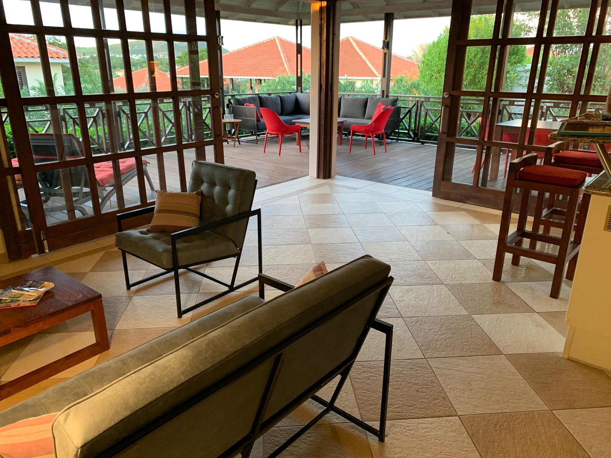 Un'ampia zona patio con pavimento a scacchi, un divano in pelle, una poltrona rossa e un angolo bar con sgabelli.