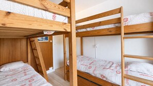 A bunk bed room with wooden frames and patterned bedding. - 2-room apartment, 6 pers., south-facing balcony, pets allowed (Les Menuires)