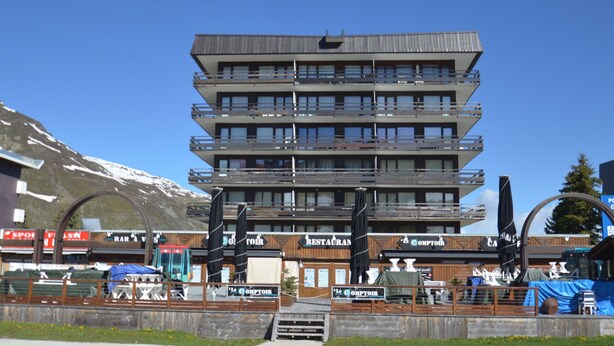 A multi-story hotel with balconies, a ski lift in the background, and signs for restaurants and bars. - 2-room apartment, 6 pers., south-facing balcony, pets allowed (Les Menuires)