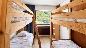 A room with bunk beds, a window with a view of a green landscape, and a radiator.