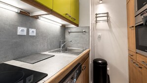 A modern kitchen with a built-in oven, a sink, and a dish drying rack.