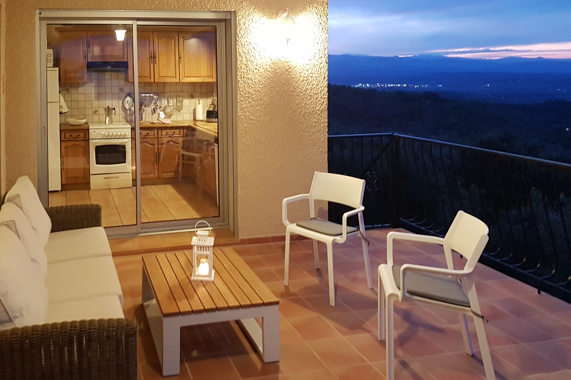 En balkon med et tekøkken, en sofa, to stole og et bord.