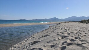 Une plage avec un ciel dégagé et des montagnes en arrière-plan.