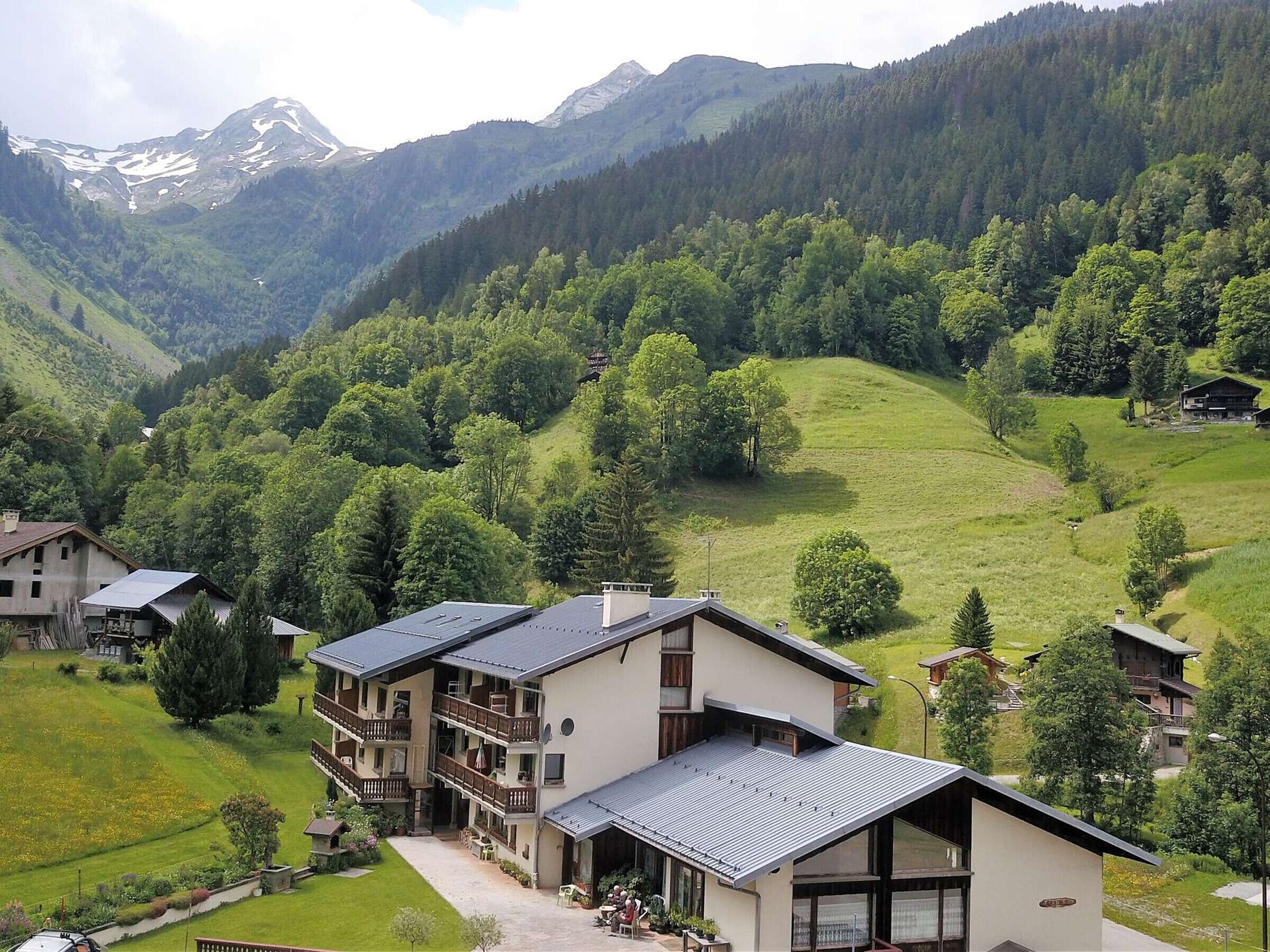 Monikerroksinen hotelli, jossa on parvekkeet, sisäpiha ja vuoristomaisema taustalla.