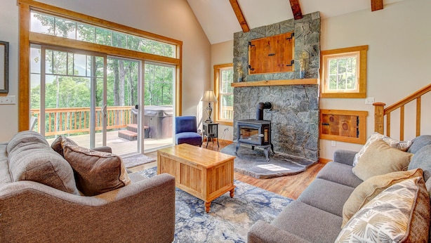 A spacious living room with a stone fireplace, large windows, and a deck. - Manchester,  Mt Equinox Views, Hot Tub, Horse-show,golf,skiing,hiking,fishing (Sunderland)
