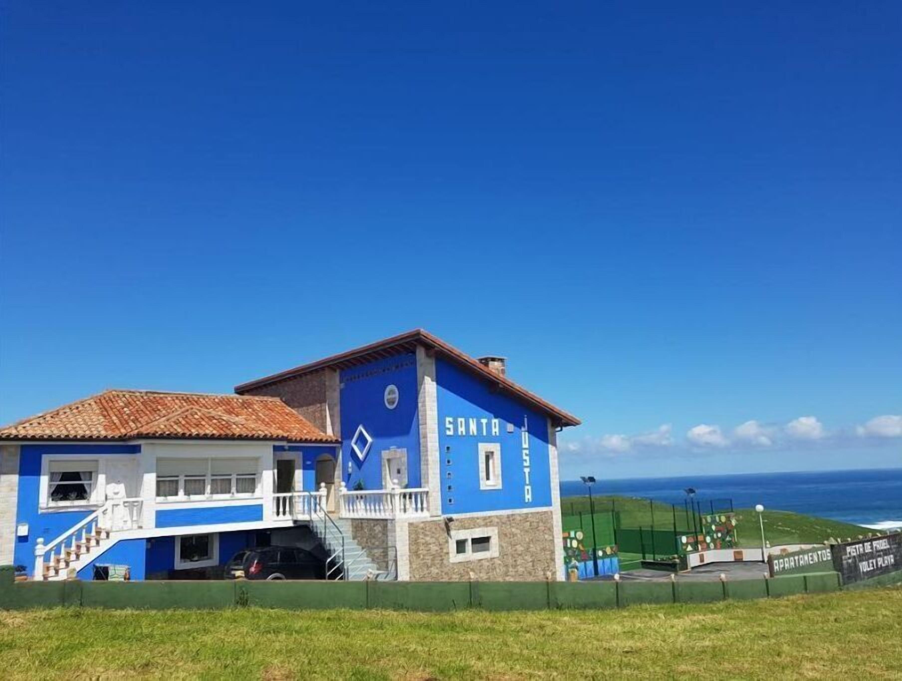 Een blauw gebouw met een betegeld dak, met de tekst 'SANTA VIOLET PLAT', en uitzicht op de oceaan.