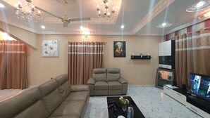 Una sala de estar con sofá, sillón, televisión y elementos decorativos.