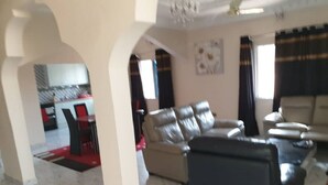 A living room with a sofa, a coffee table, and a dining area with chairs.
