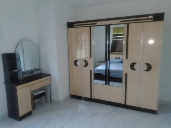 Une chambre à coucher avec une armoire, un bureau et un miroir.