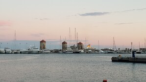 A marina with multiple boats docked, a pier with a person standing, and two windmills in the background. - Aramis Boutique House, Medieval Old-Town Rhodes (Rodos)