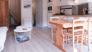 A modern kitchen with wooden cabinets, a dining table, and chairs. - Cosy Apt with Pool Access, Near Slopes & Shops, Sleeps 3 (Arêches-Beaufort)