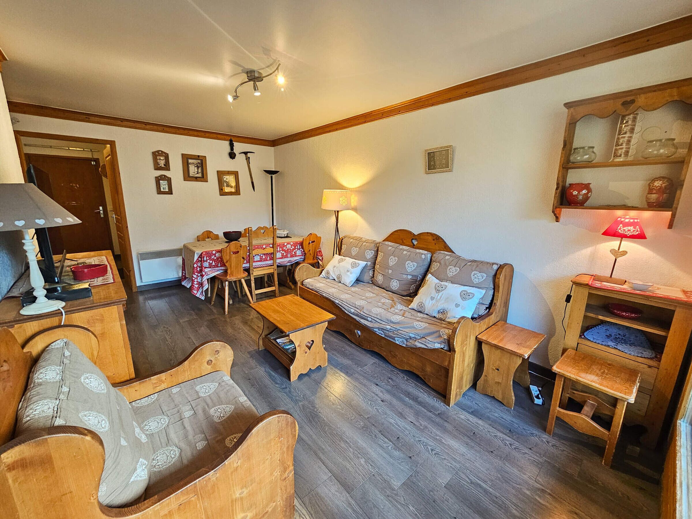 A cozy living room with a wooden sofa, matching chairs, a dining table, and a small wooden cabinet.