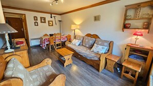 Un salon chaleureux avec un canapé en bois, des fauteuils assortis, une table à manger et un petit meuble en bois.