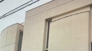 A building with a textured facade, rectangular windows, and a visible power line.
